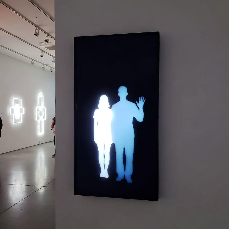 LED wall installation in gallery — two glowing silhouettes